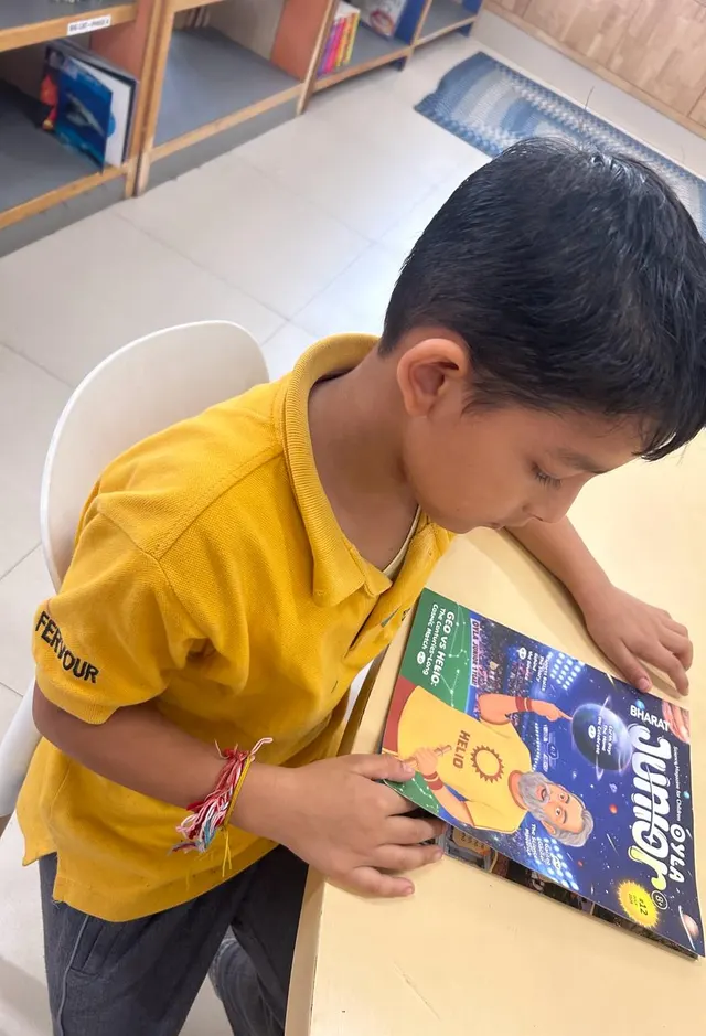 A child in a yellow shirt reading OYLA Junior at a school table.