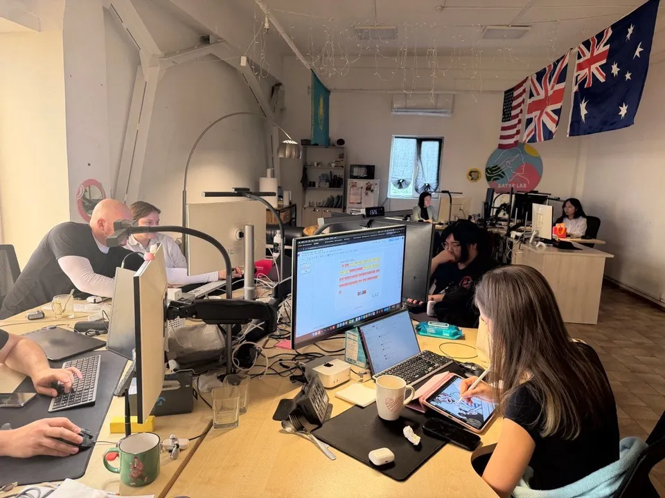 The OYLA team working at their desks, with a drawing tablet in the foreground.