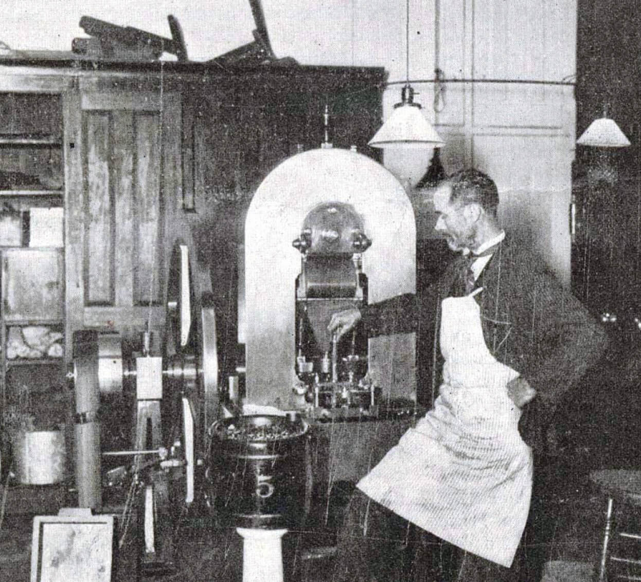 A man in an apron standing in front of a machine, examining the history and value of coins.