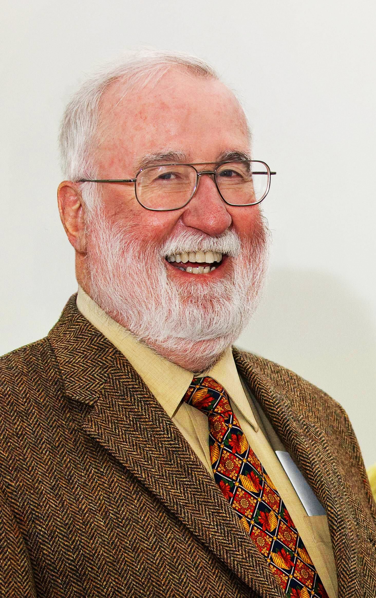 A man with a beard and glasses is smiling.