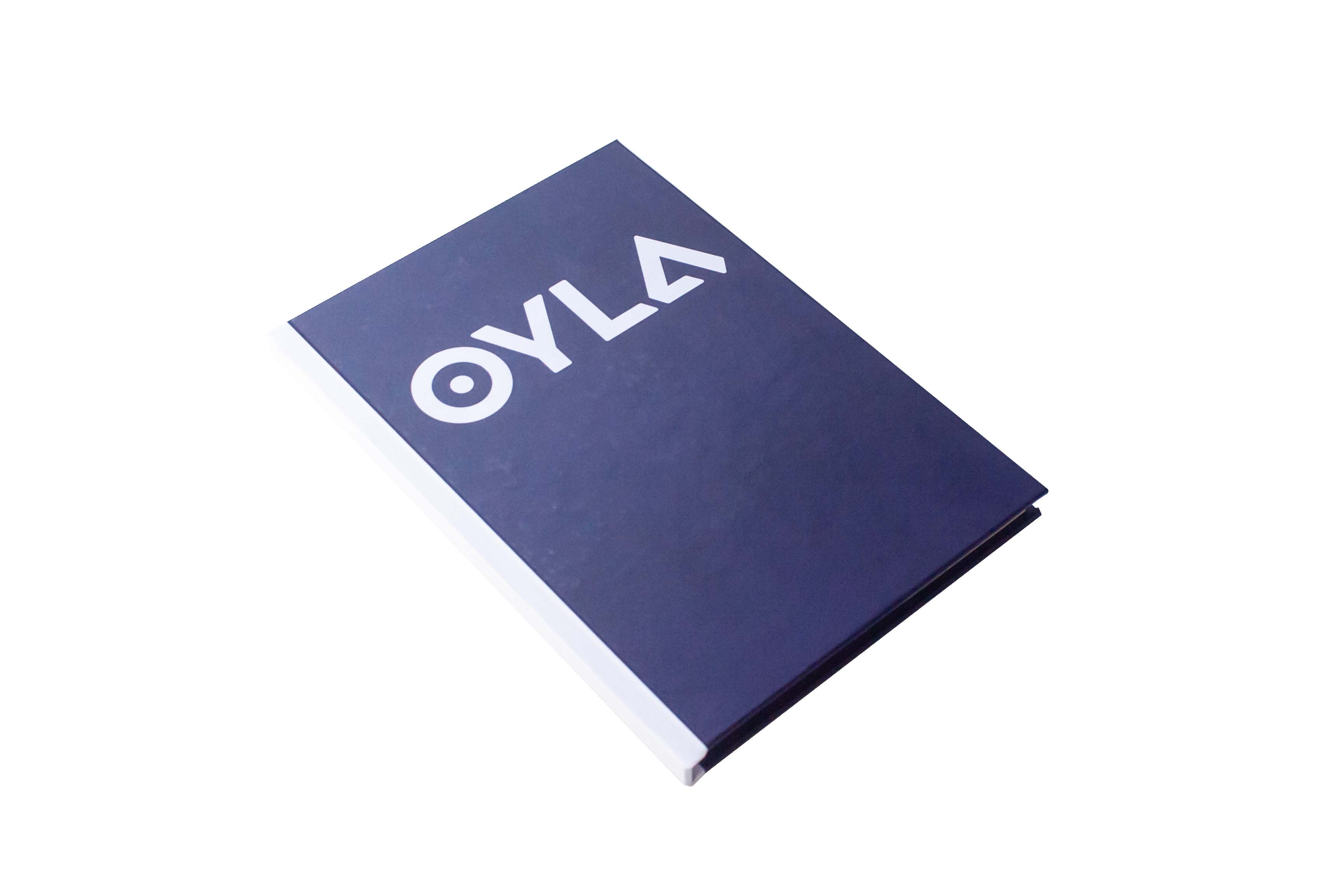 A book with a dark cover titled "oyla" lying on a white surface.