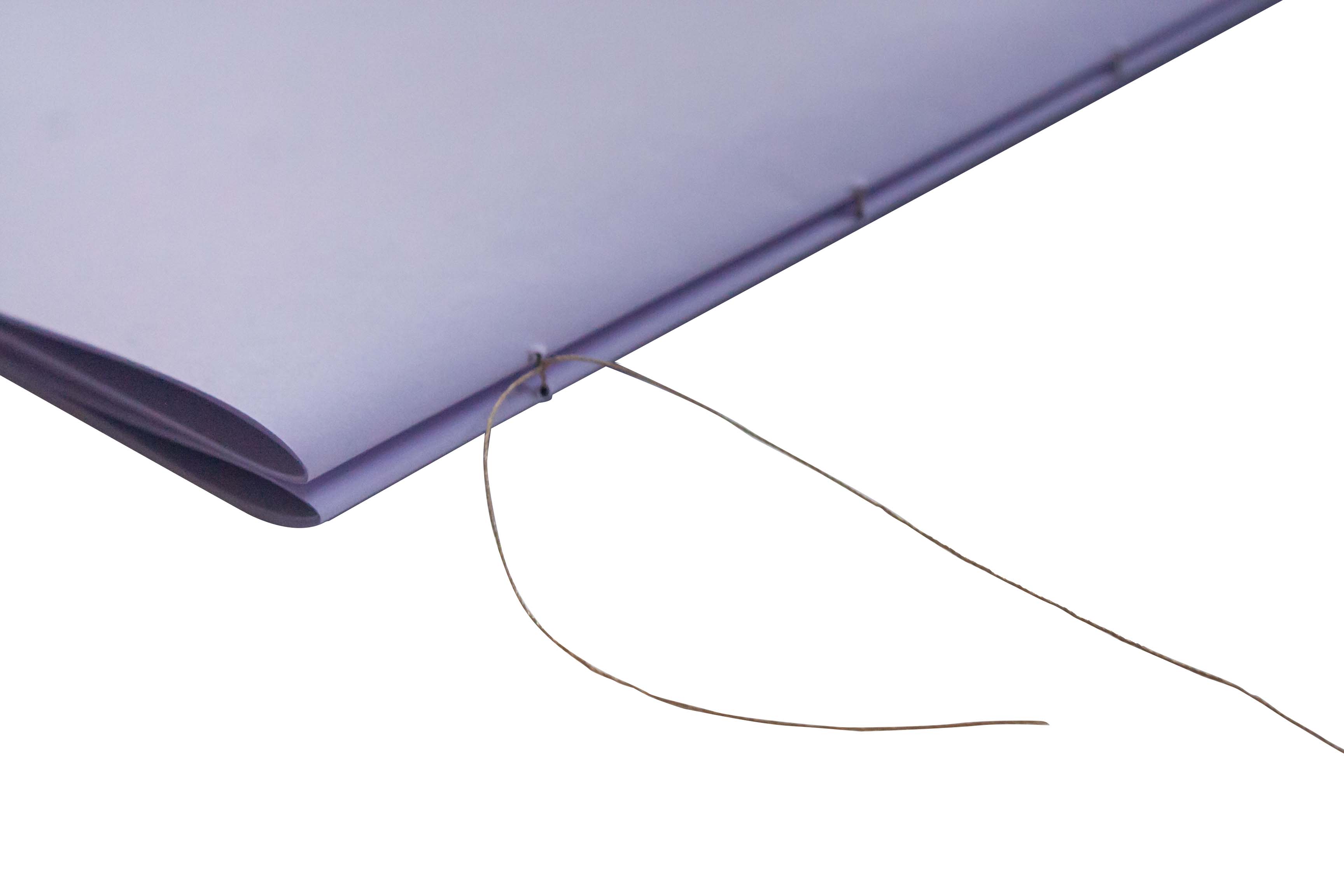 A needle threading through paper against a white background.