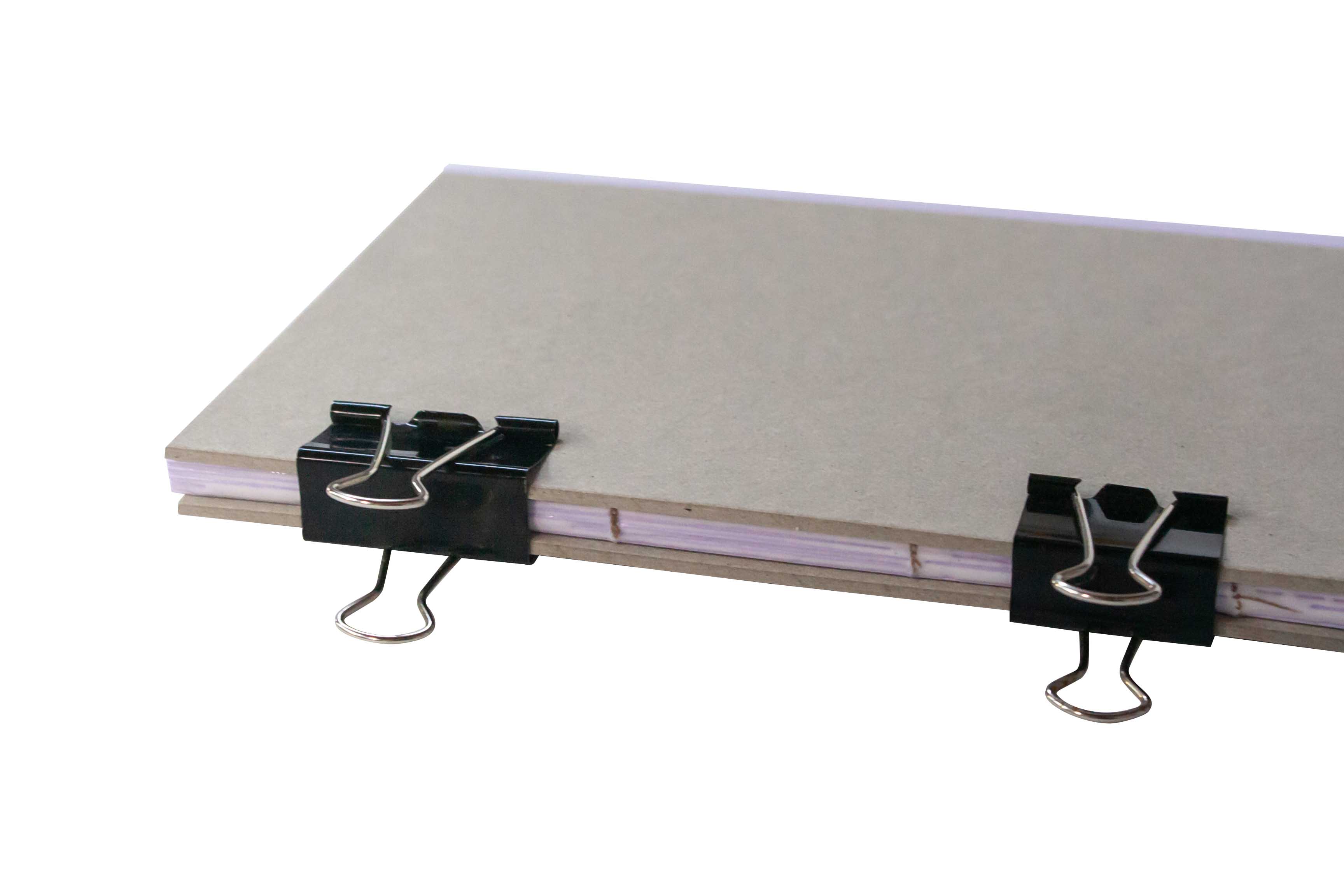 Binder clips securing a stack of papers on a hard surface.