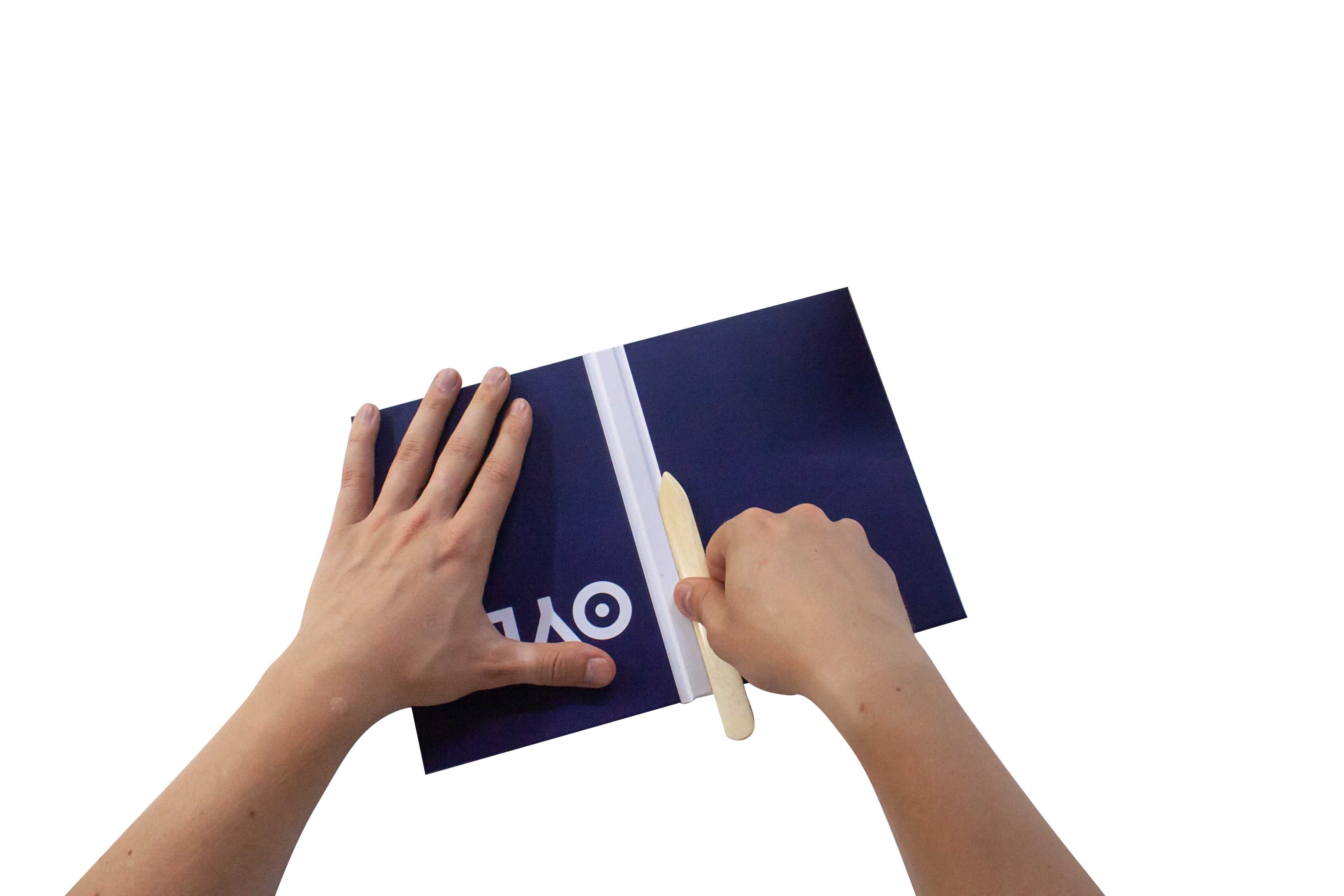 Hands using a tool to smooth out a film or sticker on a flat surface.